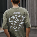 Person wearing a green t-shirt with 'Wear Love' text on the back, standing outdoors.